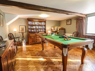 A room with a pool table and wooden furniture including a cabinet with blue and white plates at The Stables At Cae Gwyn in Ruthin