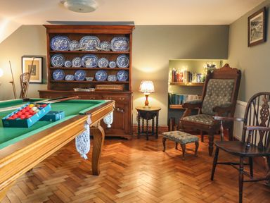 A game room with a pool table and a cabinet of blue and white plates at The Stables At Cae Gwyn in Ruthin