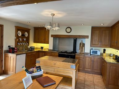 A kitchen with wooden cabinets an island a dishwasher and various appliances at The Stables At Cae Gwyn in Ruthin