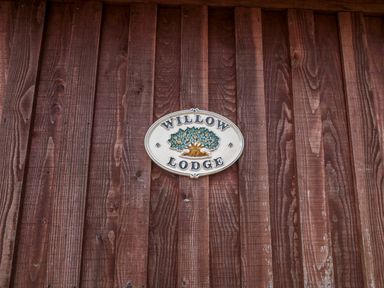 A wooden wall with a sign reading Willow Lodge near Lyme Regis