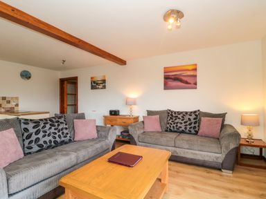 A living room with two sofas a wooden coffee table lamps and wall pictures at The Willow Lodge near Lyme Regis