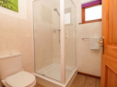 A bathroom with a toilet a glass shower enclosure a towel rack and a window at The Willow Lodge near Lyme Regis