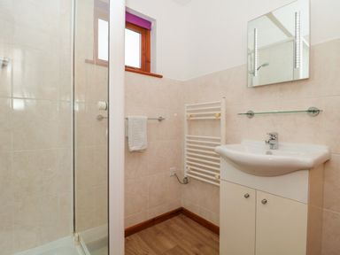 A bathroom with a shower enclosure a sink with cabinet a towel rail and a mirror at The Willow Lodge near Lyme Regis