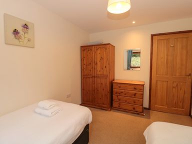 A bedroom with two single beds wooden wardrobe and chest of drawers at The Oak Lodge near Lyme Regis