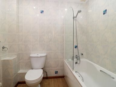 A bathroom with a toilet and a bathtub with a shower at The Oak Lodge near Lyme Regis