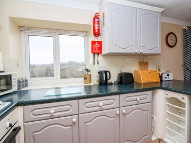 A kitchen with cabinets a window a toaster a kettle a microwave and kitchen utensils at The Hayloft Cottage Apartment near Lyme Regis