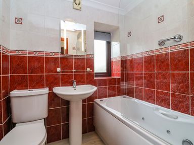 A bathroom with a toilet sink mirror and bathtub near a window at The Hayloft Cottage Apartment near Lyme Regis