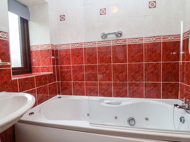 A bathroom with a bathtub sink and tiled walls near Lyme Regis