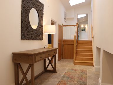 A hallway with wooden console table lamp decorative mirror stairs and a rug at The Anchorage @ Nables Farm in Upper Seagry