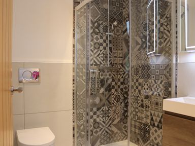 A bathroom with a toilet shower with patterned tiles and a sink at The Anchorage @ Nables Farm in Upper Seagry