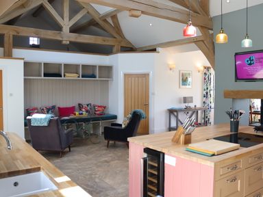 A kitchen and seating area with wooden beams and colorful cushions at The Anchorage @ Nables Farm in Upper Seagry