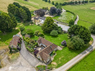 A rural property with multiple buildings surrounded by trees and green fields at The Anchorage @ Nables Farm in Upper Seagry