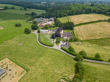An aerial view of a countryside farm with fields trees and multiple buildings at The Anchorage @ Nables Farm in Upper Seagry
