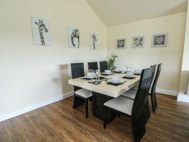 A dining room with a table set for six and animal and heart artwork on walls at Ty Cuddfan in Llangoed