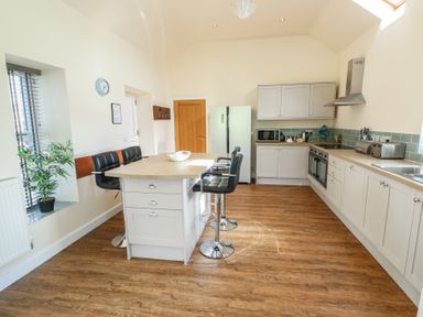 A kitchen with island stools refrigerator and cabinets at Ty Cuddfan in Llangoed