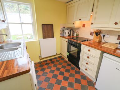 A kitchen with wooden countertops an electric stove a sink a knife block and a fridge at Carriguisnagh in Ballycastle