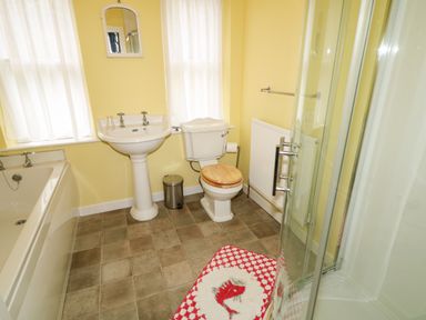A bathroom with a bathtub sink toilet shower and fish patterned rug at Carriguisnagh in Ballycastle