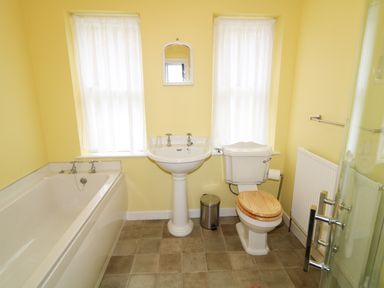 A bathroom with a bathtub sink toilet and two windows at Carriguisnagh in Ballycastle