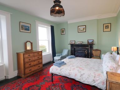 A bedroom with a bed a wooden dresser and a fireplace at Carriguisnagh in Ballycastle