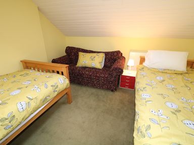 A bedroom with two single beds and a couch with a pillow at Carriguisnagh in Ballycastle