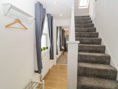 A hallway with carpeted stairs and grey curtains on windows at Monterey Mews in Torquay