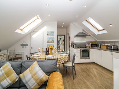 A kitchen and dining area with a table set for four under skylight windows at Monterey Mews in Torquay