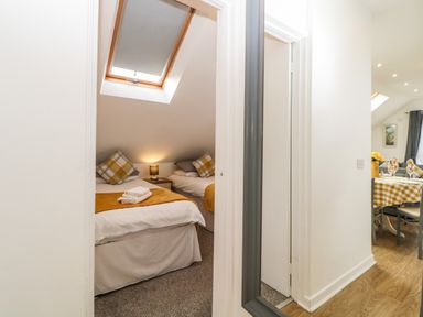 A bedroom with two single beds under a skylight and a small bedside table with a lamp at Monterey Mews in Torquay