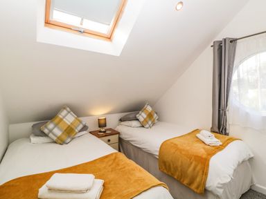 A bedroom with two single beds each with a yellow throw and plaid pillows and a skylight at Monterey Mews in Torquay