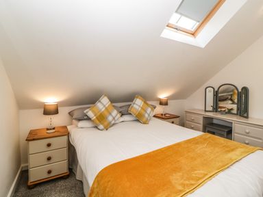 A bedroom with a bed and two bedside tables with lamps and a dressing table under a slanted ceiling with a skylight at Monterey Mews in Torquay