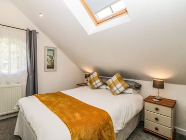 A bedroom with a double bed two bedside tables lamps a skylight window and a round window at Monterey Mews in Torquay