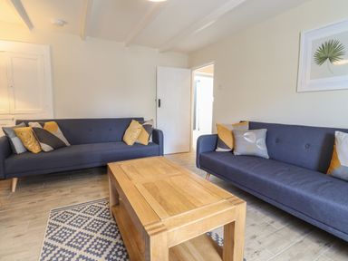 A living room with two blue sofas and a wooden coffee table at Awelfa in Newport Pembrokeshire
