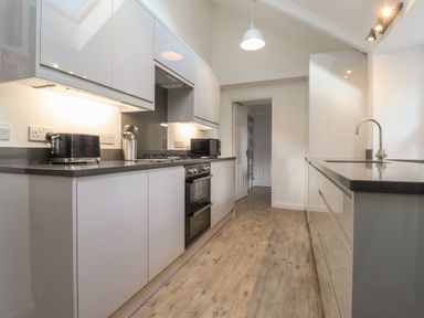 A kitchen with white cabinets black countertop built in oven toaster and microwave at Awelfa in Newport Pembrokeshire
