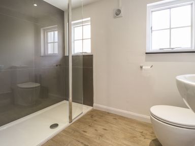 A bathroom with a shower area glass door wooden floor and a toilet at Awelfa in Newport Pembrokeshire