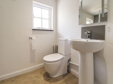 A bathroom with a toilet sink mirror window and wooden floor at Awelfa in Newport Pembrokeshire