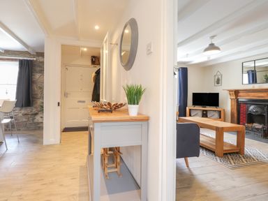 A hallway with wooden console table and a living room with TV and fireplace at Awelfa in Newport Pembrokeshire