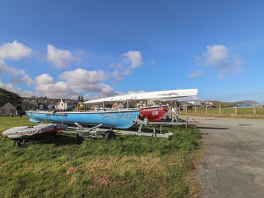Boats on trailers on grass near a paved area with houses and coastline in the background at Awelfa in Newport Pembrokeshire