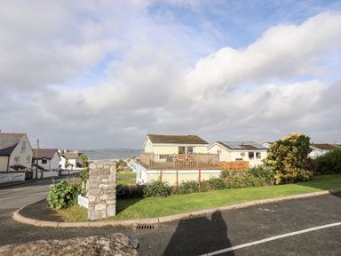 A residential street with houses and a view of water in the background at The Little Dolphins in Rhosneigr