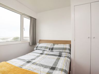 A bedroom with a bed by a window and a closet at The Little Dolphins in Rhosneigr