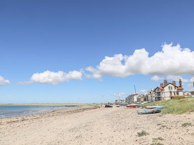 A sandy beach with boats and houses along the shore at The Little Dolphins in Rhosneigr