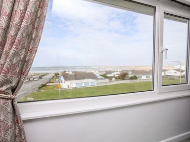A coastal view from a window with houses and grassy area at The Little Dolphins in Rhosneigr