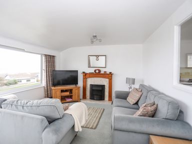A living room with two sofas a fireplace and a television at The Little Dolphins in Rhosneigr