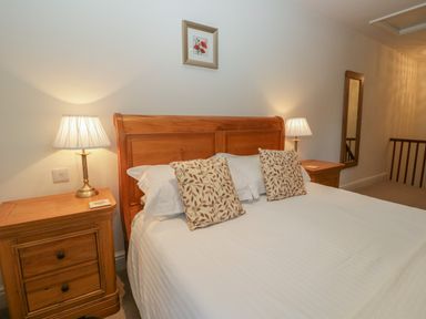 A bedroom with a wooden bed and two bedside tables with lamps at Oak Tree Cottage in Coniston