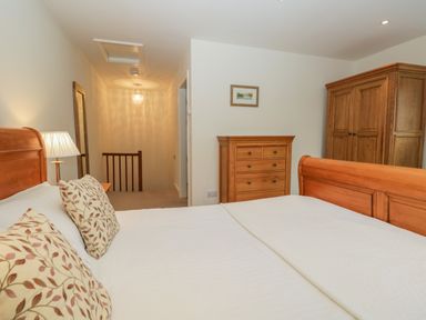 A bedroom with a wooden bed and pillows a wooden wardrobe and chest of drawers at Oak Tree Cottage in Coniston