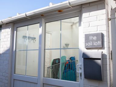 White brick exterior with a glass door a mailbox and a sign that reads the sail loft in St Ives