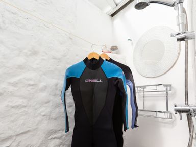 A bathroom with wetsuits hanging on a clothesline a round mirror and a shower at The Sail Loft in St Ives