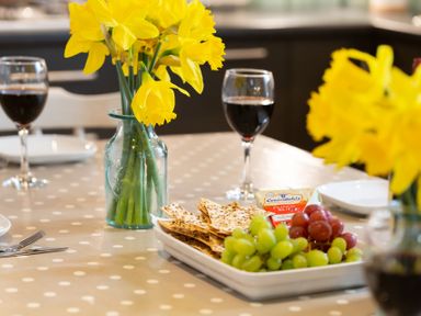 A table with yellow flowers in a vase red and green grapes crackers and two glasses of red wine at The Sail Loft in St Ives