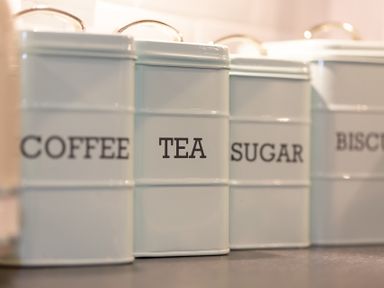 A set of white canisters labeled coffee tea sugar and biscuits on a kitchen counter at The Sail Loft in St Ives