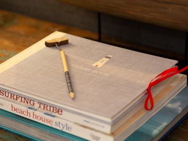 A stack of books with a guest book and a pencil on a table at The Sail Loft in St Ives