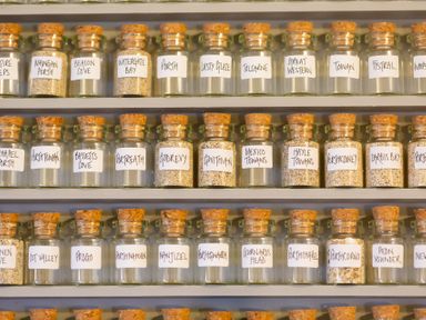 Glass bottles with cork stoppers filled with sand and labeled on shelves at The Sail Loft in St Ives