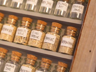 Glass jars with cork lids containing sand samples labeled with locations